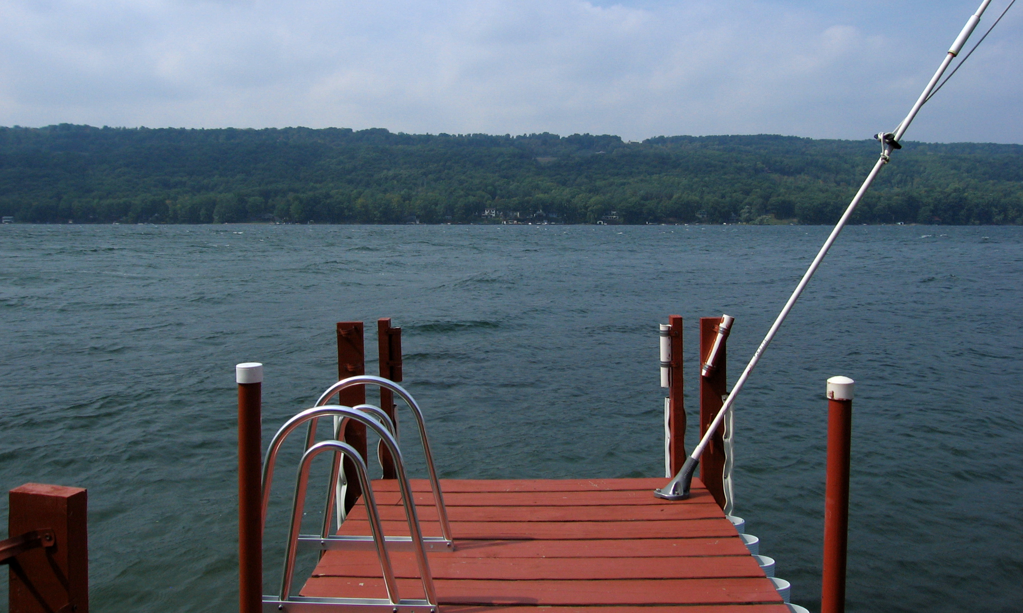 A dock on a lake with a wooded far shore.